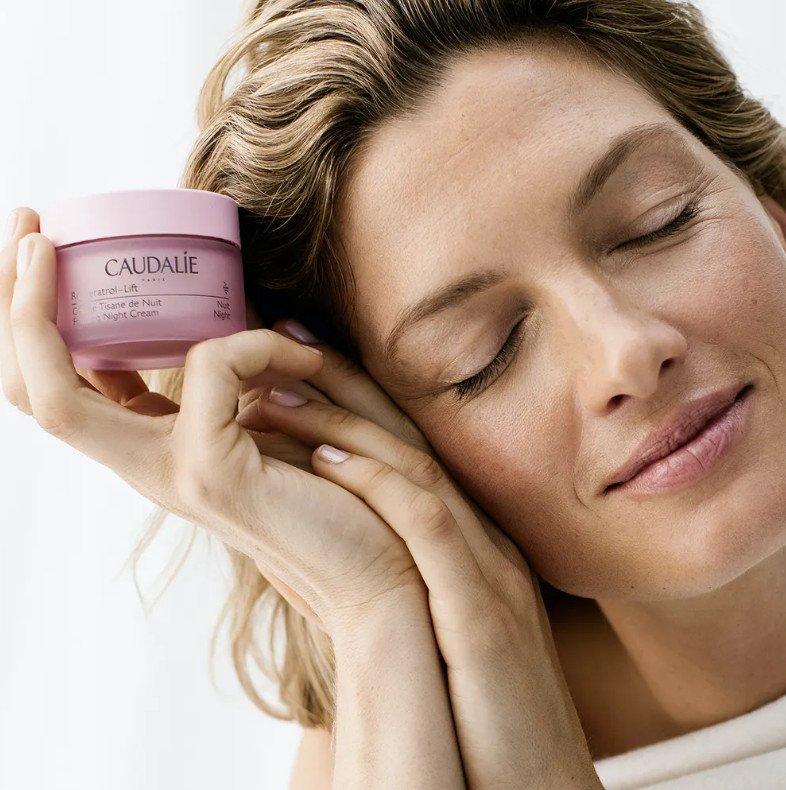 CAUDALIE Crema Tisana de Noche Resveratrol-lift  Tipo de piel : Todo tipo de pieles Necesita : Firmeza Ingredientes clave : Aceite de pepitas de uva, Escualeno de oliva, Péptidos, Resveratrol, Booster de Colágeno Vegano, Ácido hialurónico Textura : Crema Use : Por la noche, después del suero ¿Qué es?  Una nueva patente presentada con booster de colágeno vegano aún más eficaz.  Gracias a su asociación patentada de Resveratrol, ácido hialurónico y booster de colágeno vegano, la Crema Tisana de Noche antiarrugas reconfortante regenera la piel para estar bella al despertar: los rasgos están descansados y alisados, la piel está firme, el cutis está radiante.  Compuesta en más de un 98% por ingredientes de origen natural y enriquecida con escualano de oliva, su textura de crema suave y untuosa nutre la piel y le proporciona una sensación de calma.  Su complejo fitoaromático deja la piel delicadamente perfumada con notas de flores de manzanilla, agua de lavanda, hojas de naranja, tomillo rojo, salvia y menta fresca.  El compromiso de Caudalie: Envases 100% reciclables para cumplir el objetivo de "cero residuos"* Cajas fabricadas con menos papel y sin revestimiento de plástico, es decir, un 40% menos de emisión de huella carbono.**